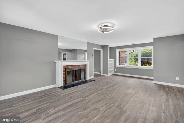 an empty room with wooden floor fireplace and windows