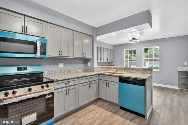 a kitchen with granite countertop a sink cabinets and wooden floor