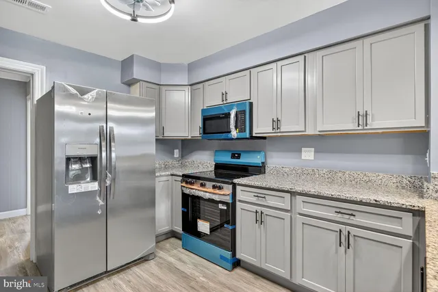 a kitchen with stainless steel appliances granite countertop a refrigerator a stove a sink and white cabinets