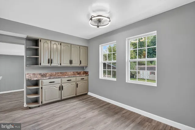 a hall with kitchen island granite countertop white cabinets and window