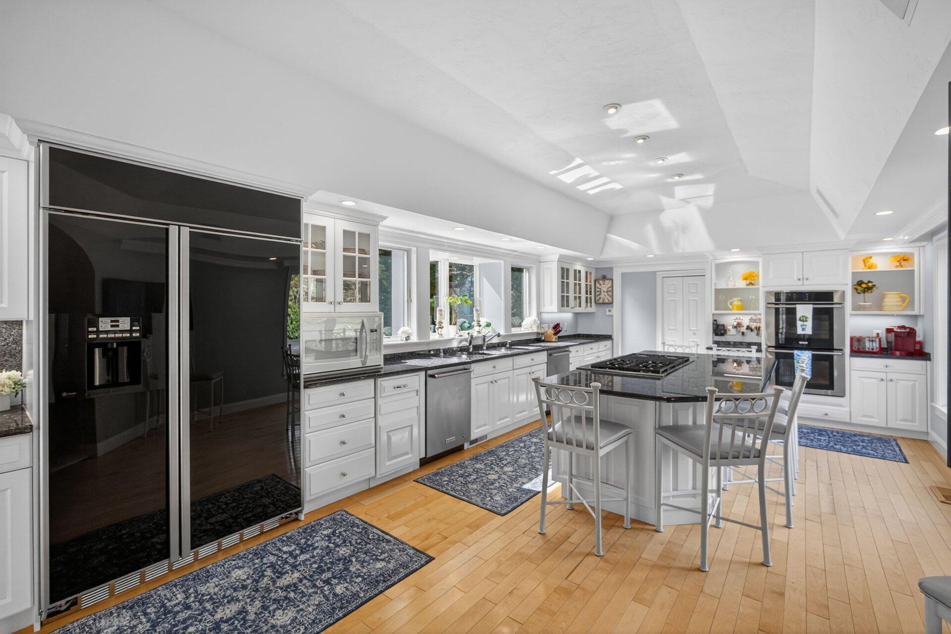 461 Wings Neck Road Pocasset, MA 02559 - Photo 16 of 42 a kitchen with stainless steel appliances kitchen island granite countertop a refrigerator a stove a dining table and chairs with wooden floor