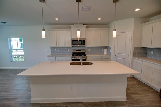 a kitchen with kitchen island a stove a sink a refrigerator and white cabinets