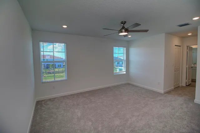 en empty room with windows and ceiling fan