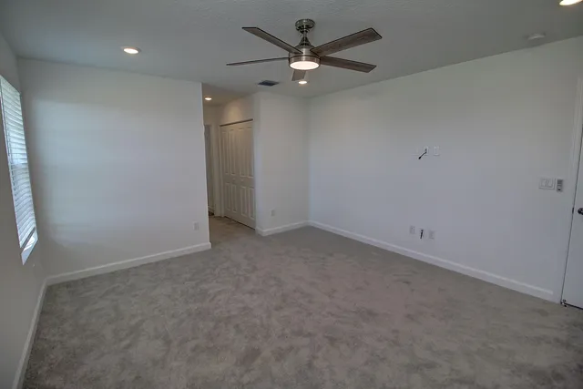an empty room with a ceiling fan and a window