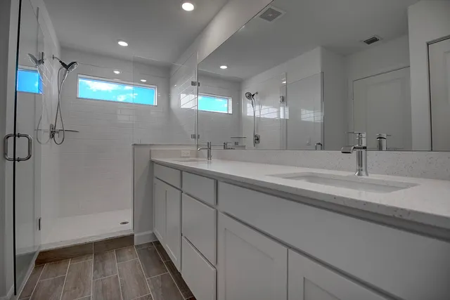 a bathroom with a double vanity sink a mirror and a shower