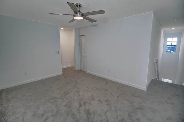 an empty room with a ceiling fan and a window