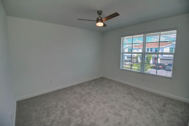 an empty room with windows and fan