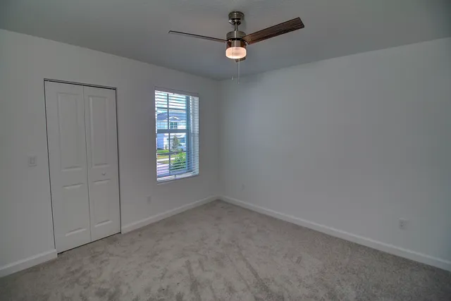 an empty room with a window and a fan