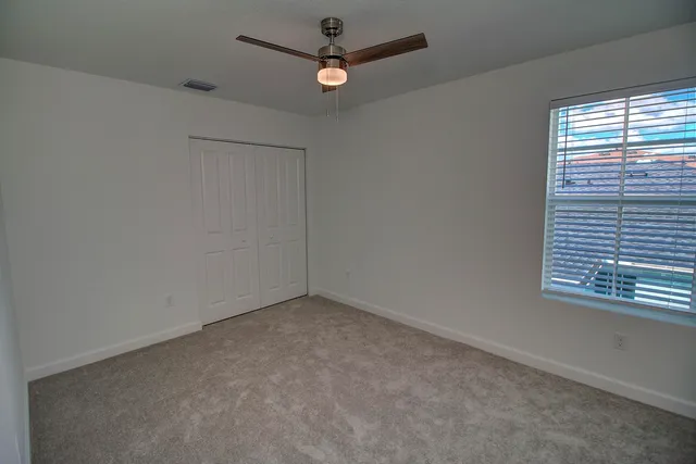 an empty room with a window and a ceiling fan