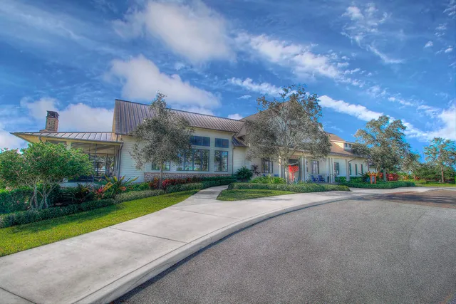 a view of a white house next to a yard with big trees
