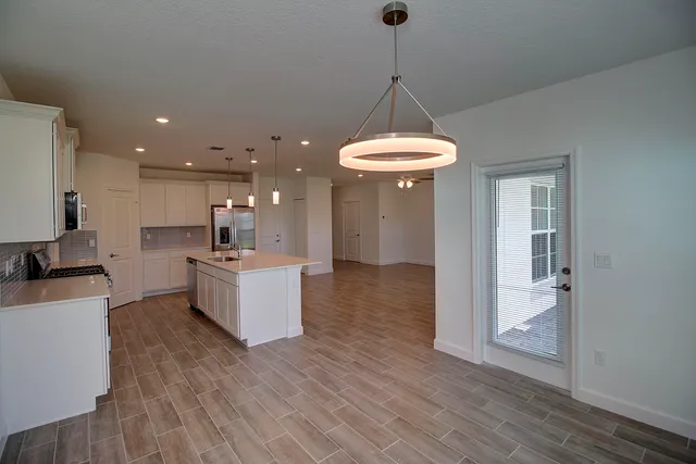 a kitchen with stainless steel appliances a chandelier and wooden floor