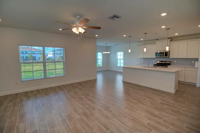 an open kitchen with kitchen island a sink dishwasher refrigerator stove and wooden floor