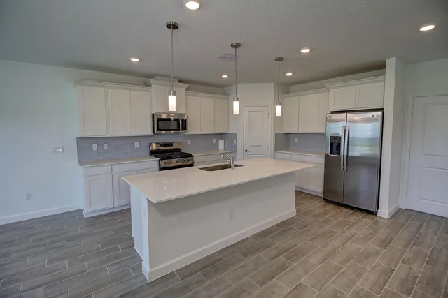 a kitchen with kitchen island stainless steel appliances a refrigerator a stove top oven and a center island
