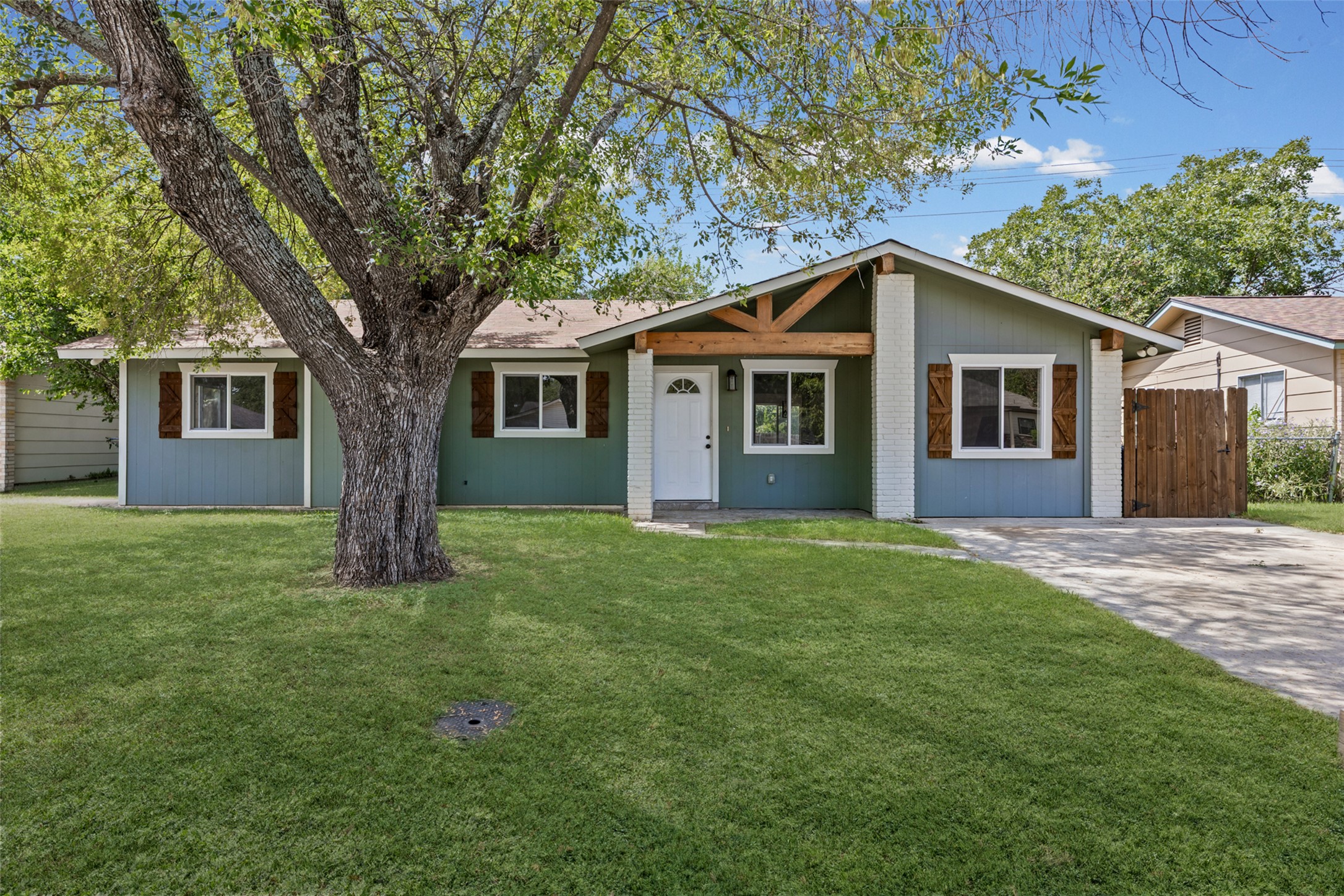 Mature trees shade the manicured front lawn of this single-story home with rustic wood accents.