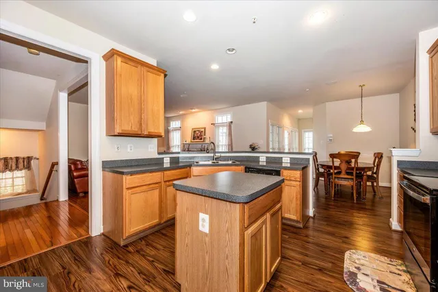 a kitchen with stainless steel appliances granite countertop wooden cabinets a sink a stove a dining table and chairs