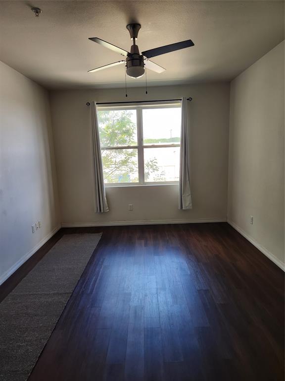 1100 West Trinity Mills Road, Unit 2013 Carrollton, TX 75006 - Photo 12 of 15 an empty room with wooden floor and windows