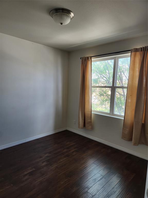 1100 West Trinity Mills Road, Unit 2013 Carrollton, TX 75006 - Photo 13 of 15 a view of an empty room with wooden floor and a window