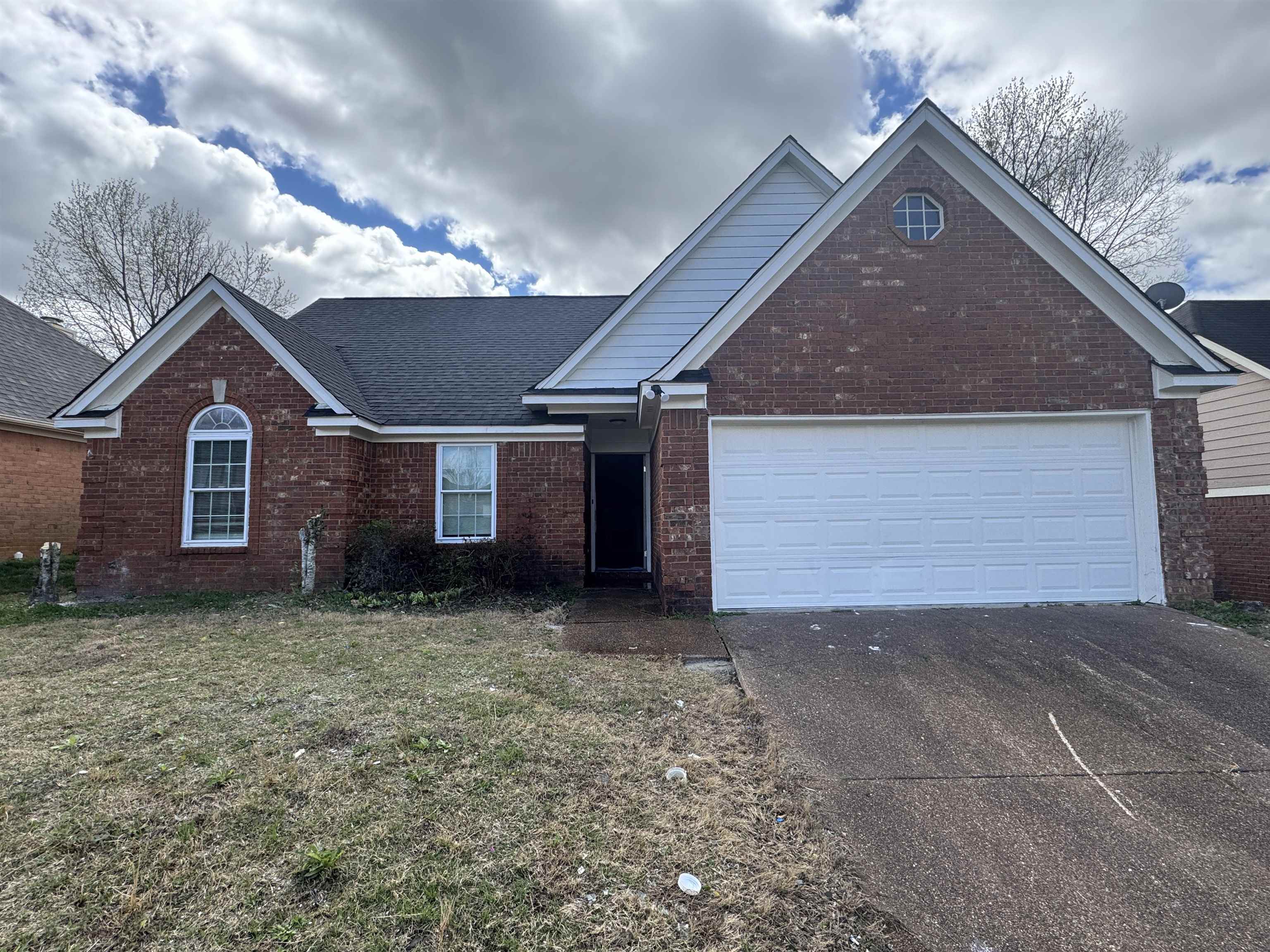 View of front of property with concrete driveway, an attached garage, brick siding, and a front yard