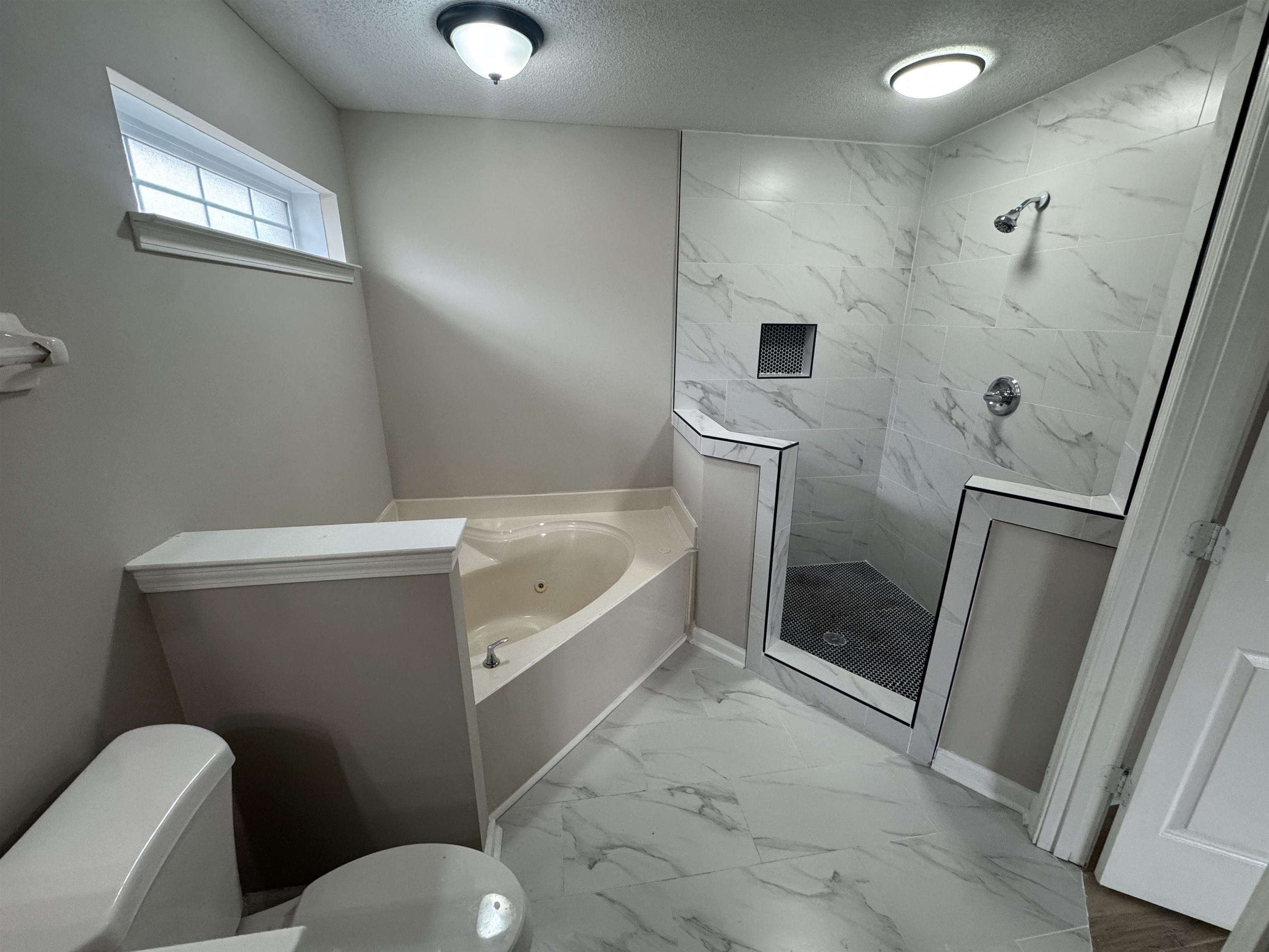 5457 Sundale Way South Memphis, TN 38135 - Photo 12 of 23 Bathroom featuring light marble finish floors, a textured ceiling, a marble finish shower, and a bath