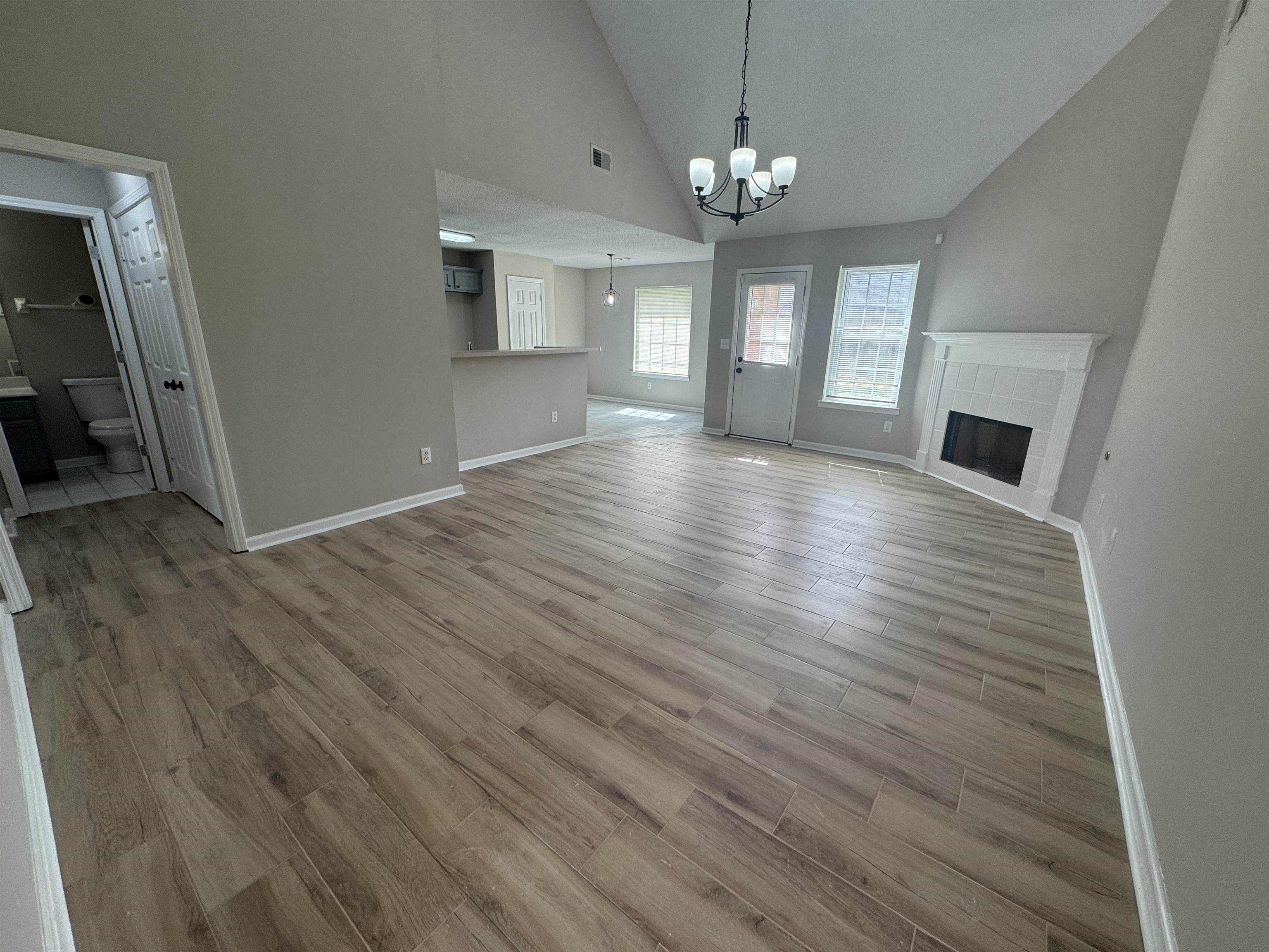 5457 Sundale Way South Memphis, TN 38135 - Photo 4 of 23 Unfurnished living room featuring vaulted ceiling, hanging lights, a tile fireplace, and light wood-style floors