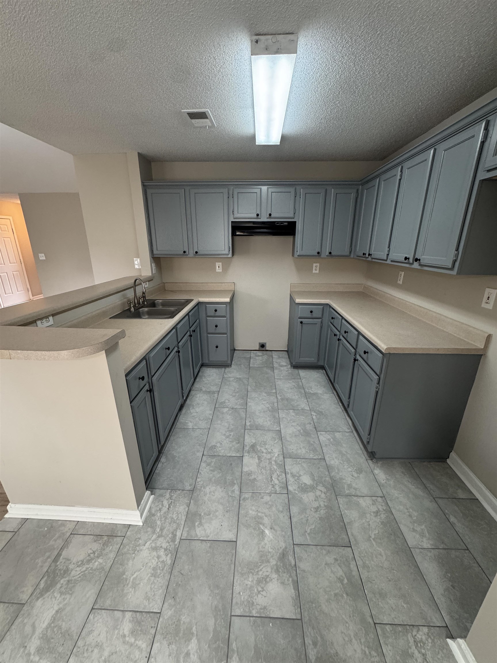 5457 Sundale Way South Memphis, TN 38135 - Photo 10 of 23 Kitchen with gray cabinetry, a peninsula, a textured ceiling, and light countertops