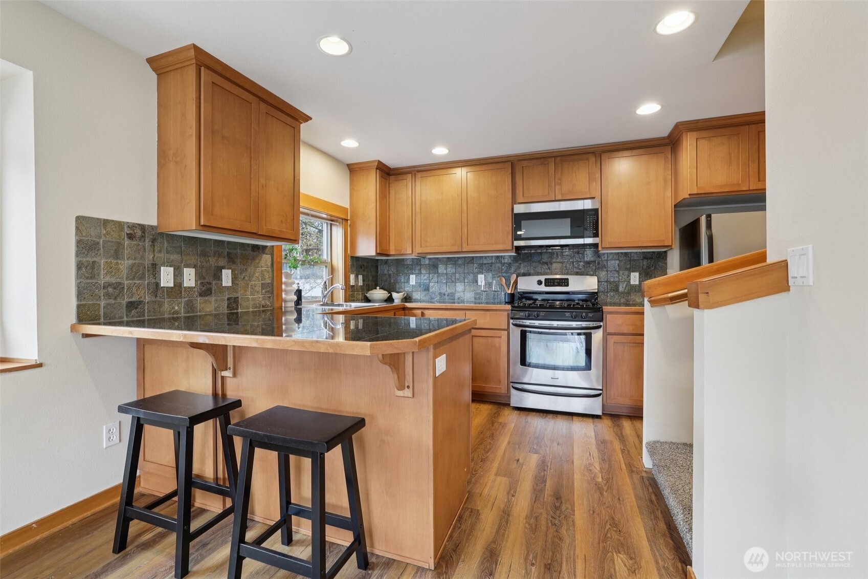 9047 17th Avenue Southwest, Unit A Seattle, WA 98106 - Photo 16 of 29 a kitchen with granite countertop a stove top oven a sink a dining table and chairs