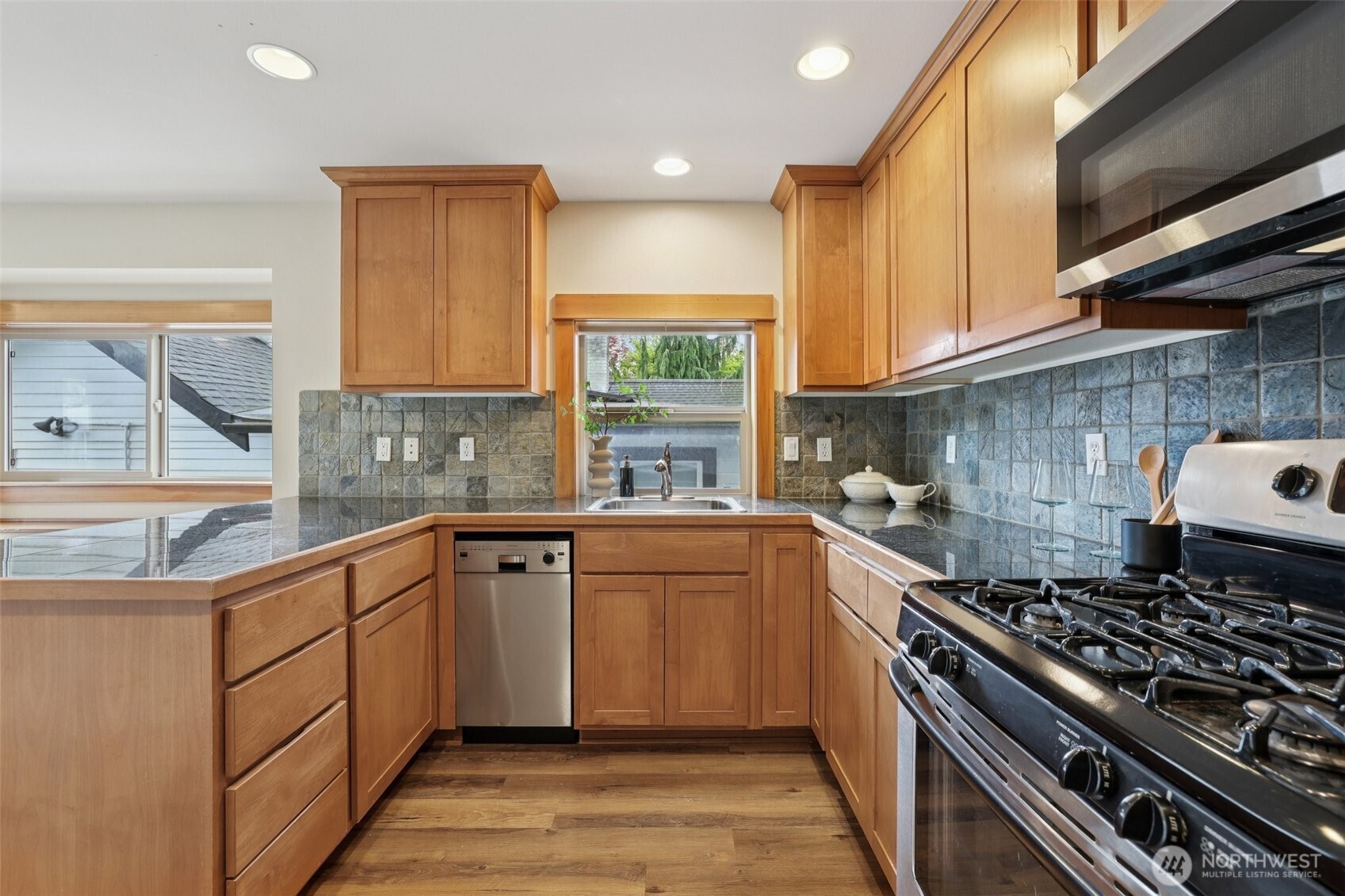 9047 17th Avenue Southwest, Unit A Seattle, WA 98106 - Photo 18 of 29 a kitchen with stainless steel appliances granite countertop a stove a sink dishwasher and cabinets with wooden floor