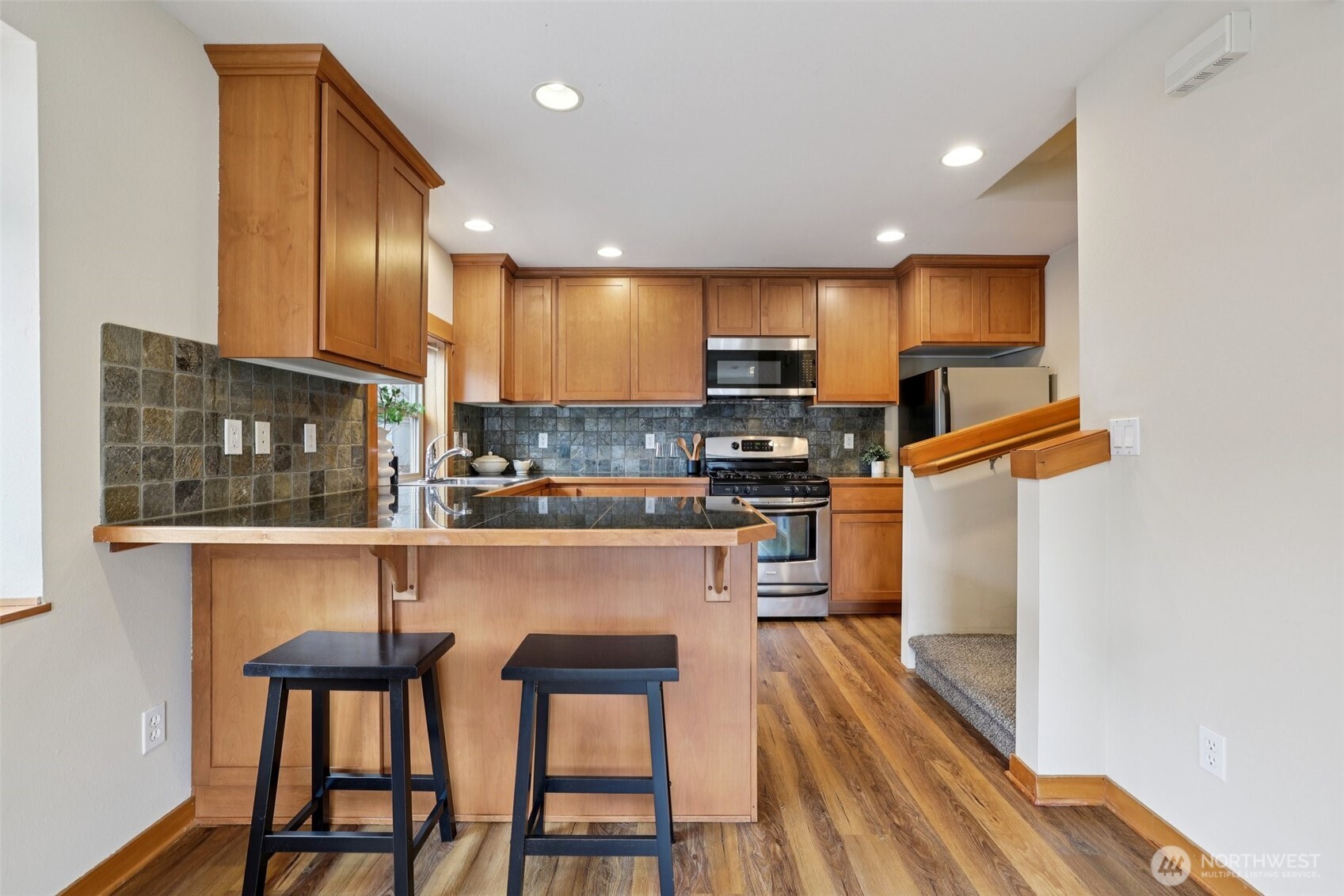 9047 17th Avenue Southwest, Unit A Seattle, WA 98106 - Photo 2 of 29 a kitchen with stainless steel appliances granite countertop a refrigerator a stove top oven and a sink with wooden floor