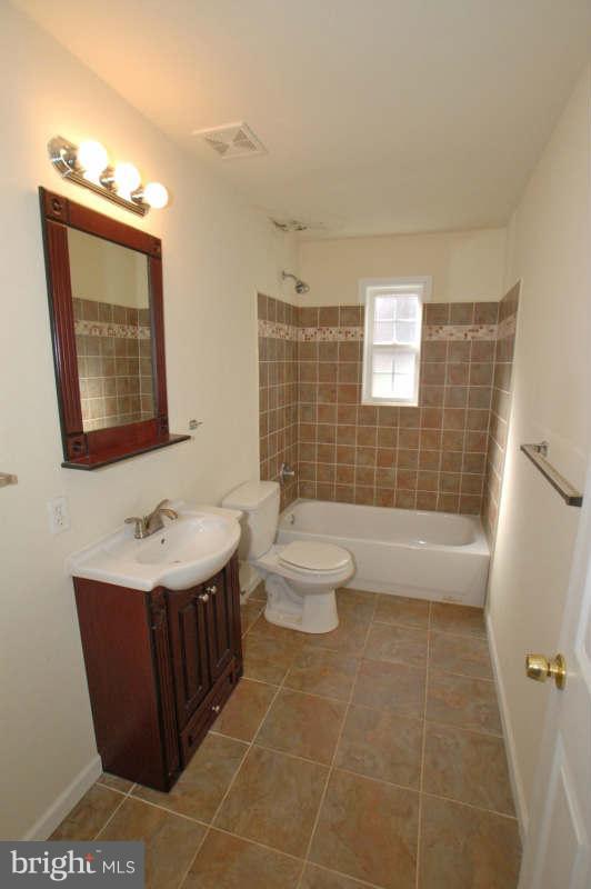 3641 Clifmar Road Baltimore, MD 21244 - Photo 19 of 27 a bathroom with a toilet a sink a mirror a shower a vanity and window