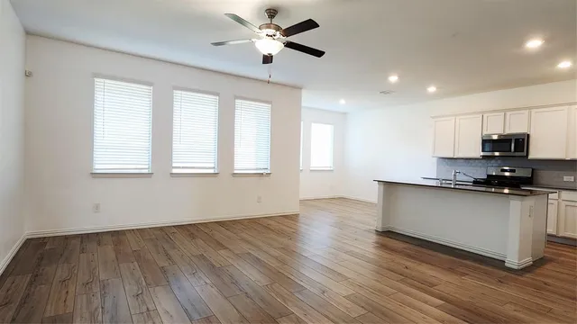 a kitchen with granite countertop wooden floors stainless steel appliances and a window