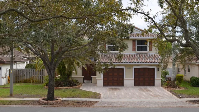 a front view of a house with yard garage and tree