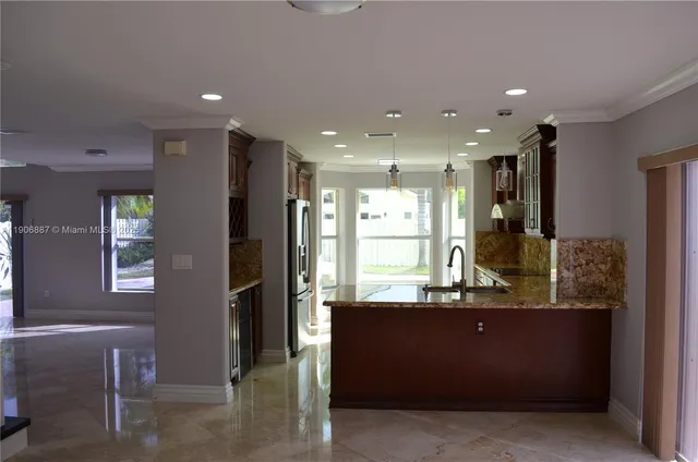 a kitchen with kitchen island granite countertop a refrigerator and a sink