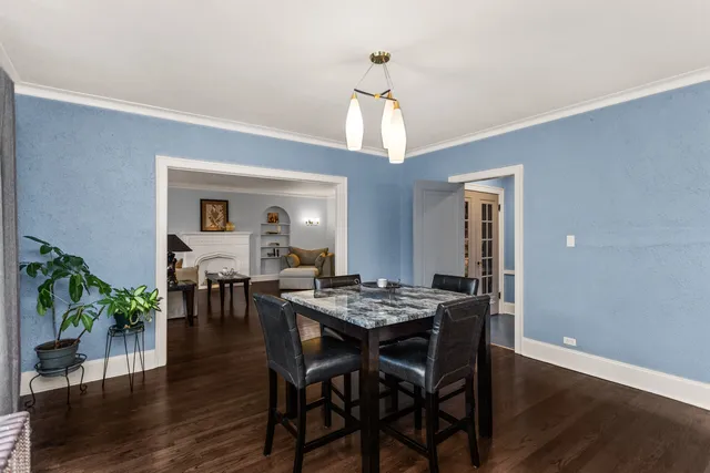 a dining room with wooden floor a chandelier a wooden table and chairs