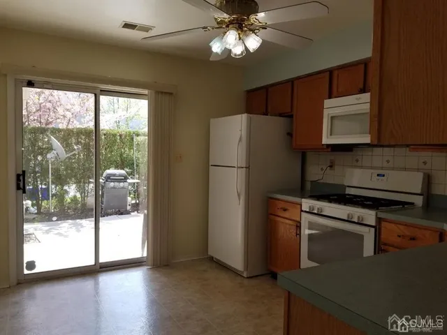 a kitchen with stainless steel appliances granite countertop a refrigerator a sink a stove and white cabinets with wooden floor