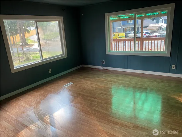 a view of an empty room with wooden floor and a window