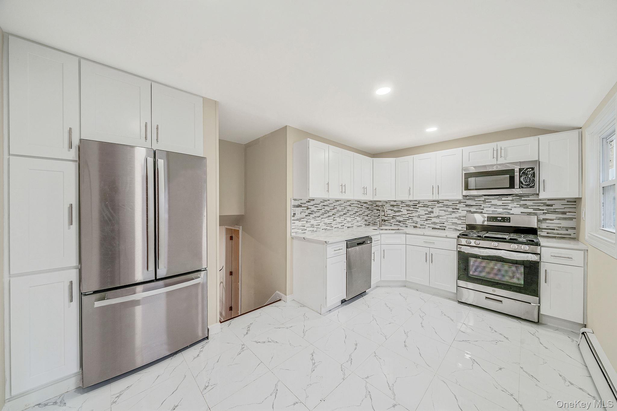 119 Foster Road Ronkonkoma, NY 11779 - Photo 13 of 26 Kitchen with stainless steel appliances, a baseboard heating unit, white cabinets, light marble finish floors, and recessed lighting