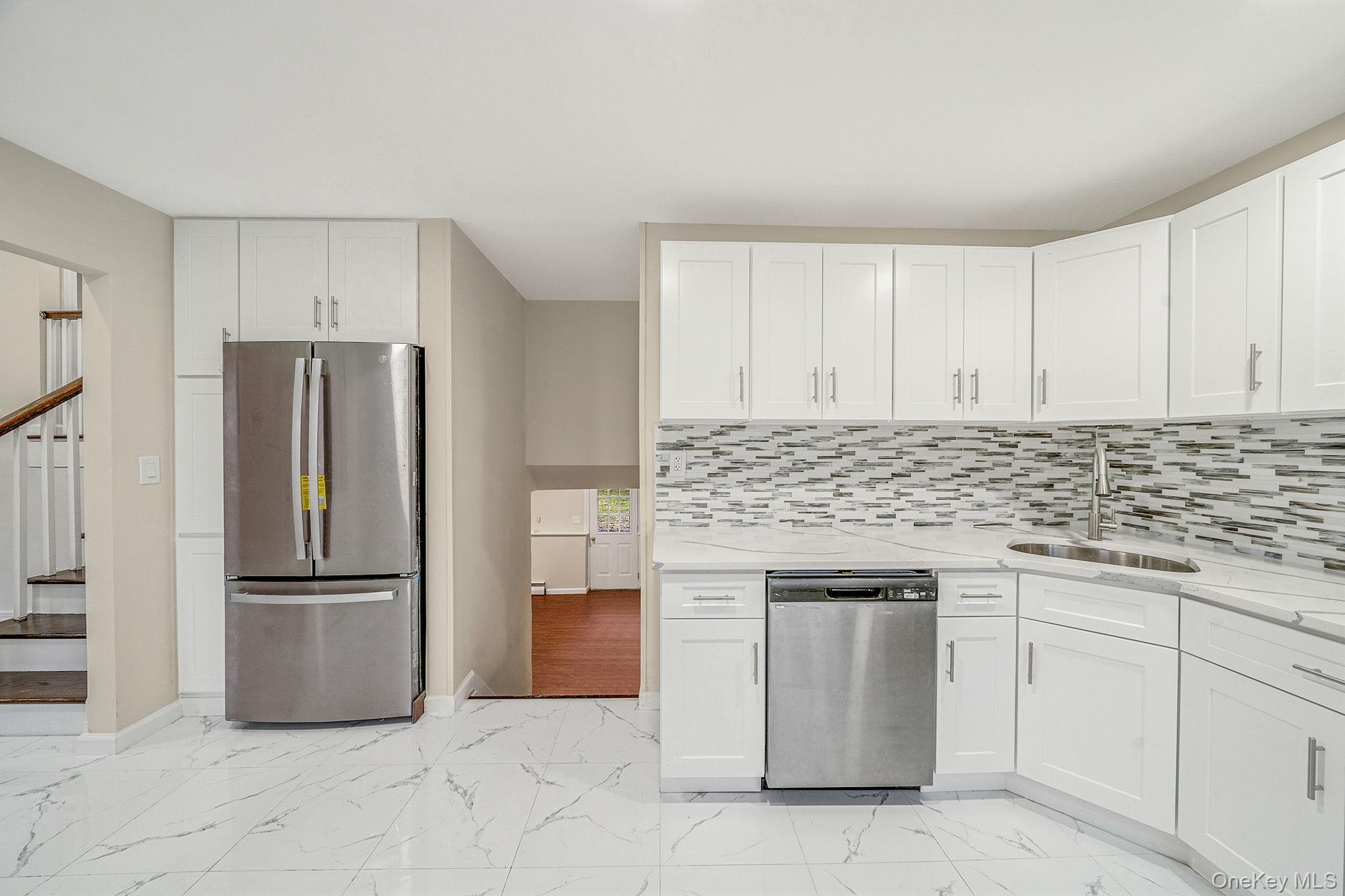 119 Foster Road Ronkonkoma, NY 11779 - Photo 15 of 26 Kitchen featuring appliances with stainless steel finishes, light marble finish floors, white cabinetry, and light stone countertops