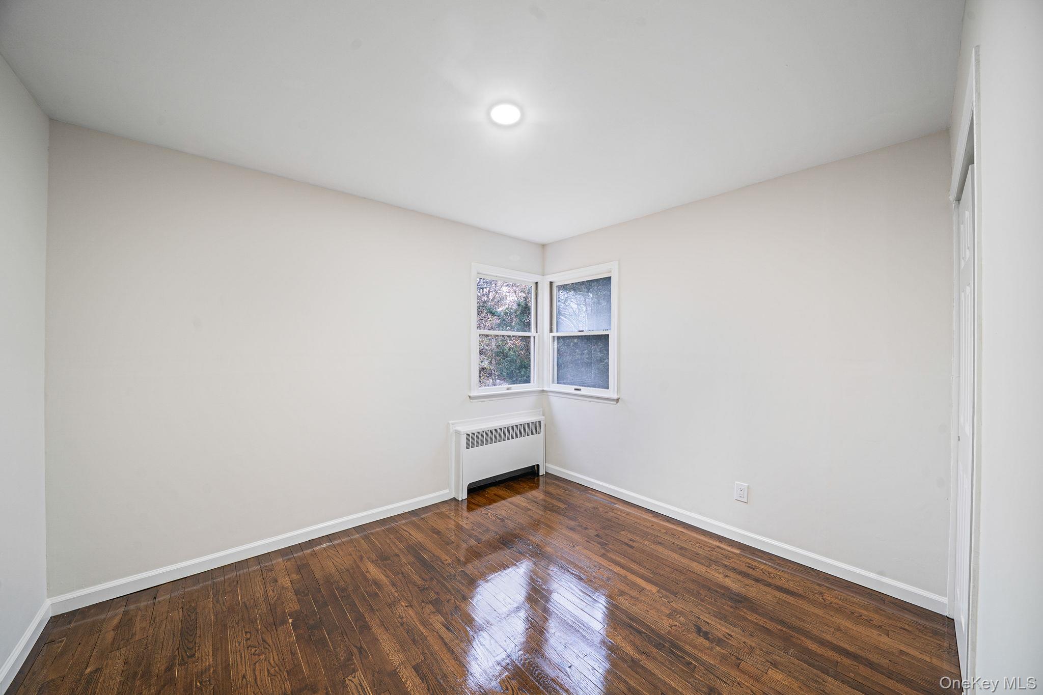 119 Foster Road Ronkonkoma, NY 11779 - Photo 20 of 26 Spare room with radiator heating unit and dark wood-style floors