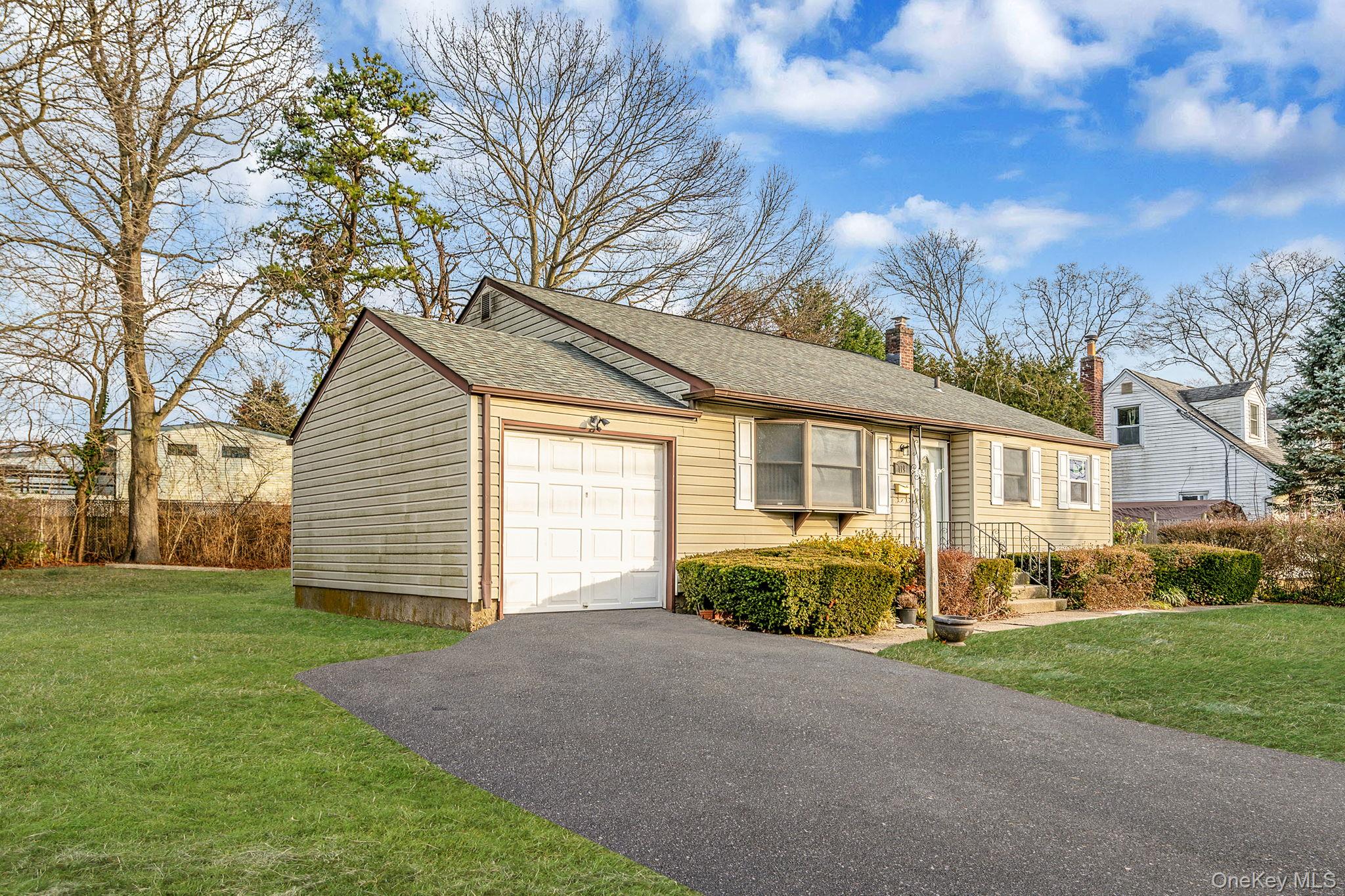 119 Foster Road Ronkonkoma, NY 11779 - Photo 2 of 26 View of front of house with a front lawn, an attached garage, asphalt driveway, roof with shingles, and a chimney