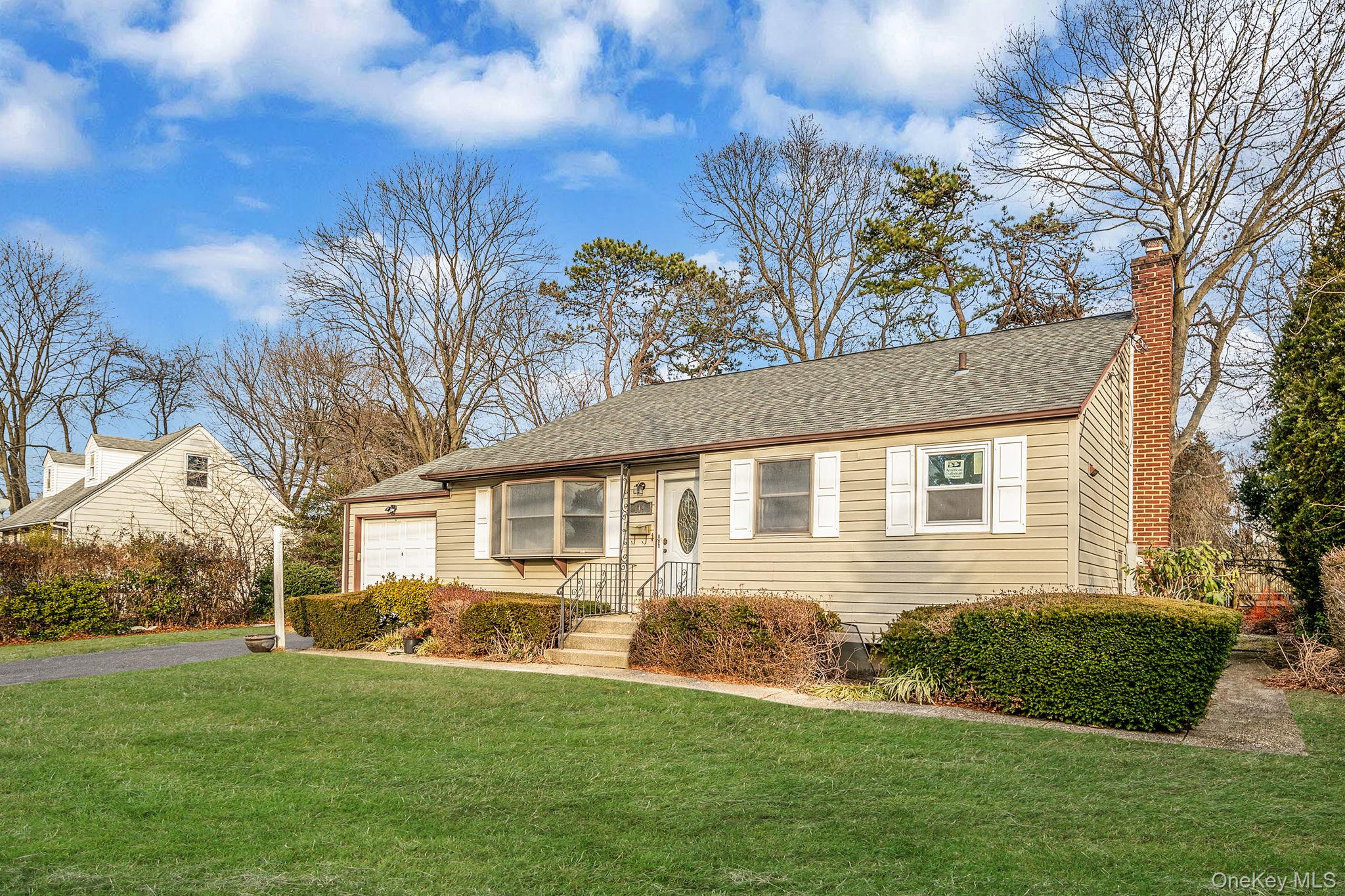 119 Foster Road Ronkonkoma, NY 11779 - Photo 3 of 26 View of front of property with a front yard, roof with shingles, a chimney, and driveway