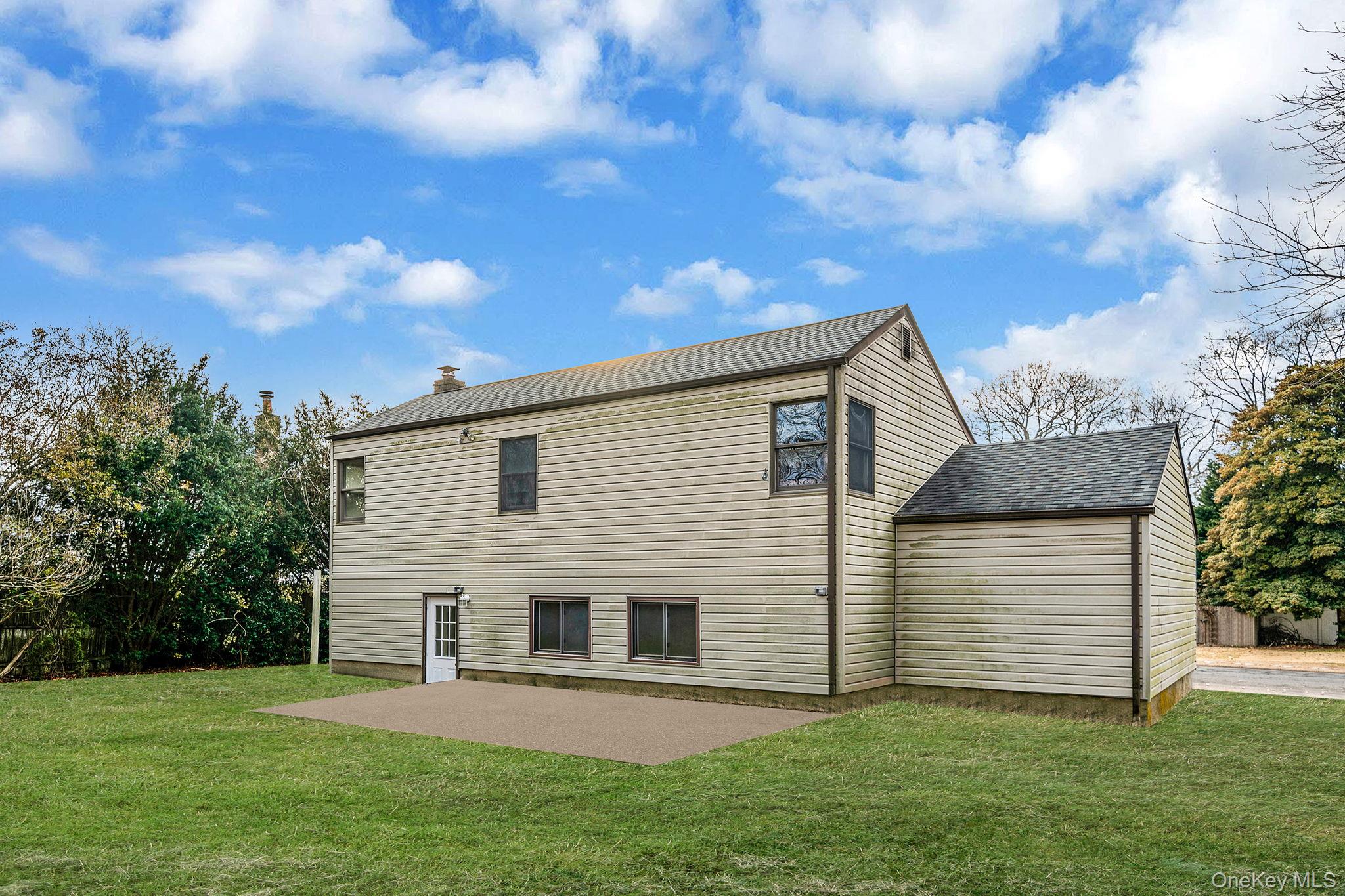 119 Foster Road Ronkonkoma, NY 11779 - Photo 6 of 26 Back of property with a patio, a yard, a shingled roof, and a chimney