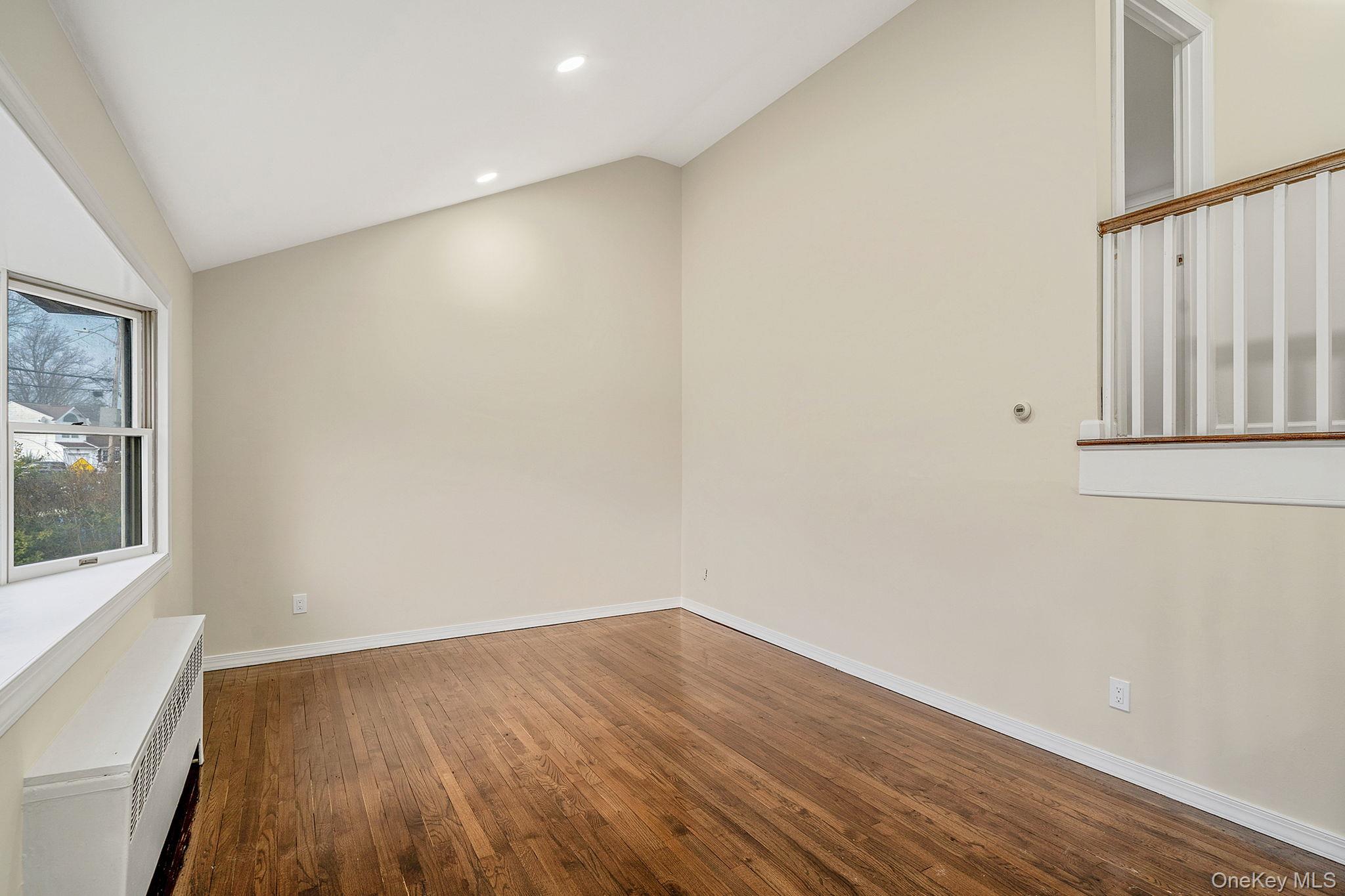 119 Foster Road Ronkonkoma, NY 11779 - Photo 9 of 26 Spare room featuring vaulted ceiling, radiator, dark wood-type flooring, and recessed lighting