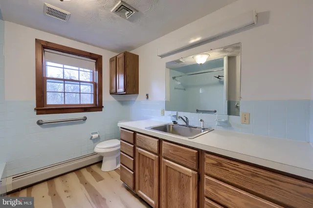 a view of empty room with wooden floor and kitchen