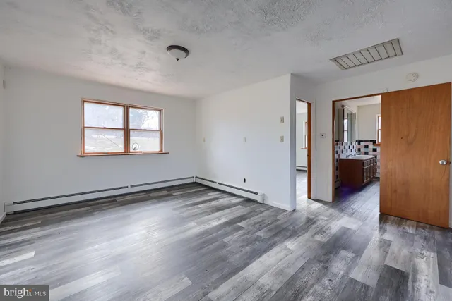 a view of an empty room with window and wooden floor