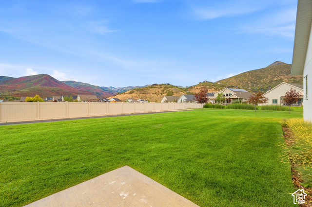 1295 North Canyon View Road Midway, UT 84049 - Photo 48 of 52 Expansive lawn area with a concrete pad, surrounded by a light-colored privacy fence and distant mountains