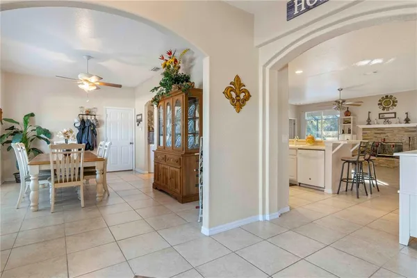 a living room with furniture a chandelier and a dining table with kitchen view
