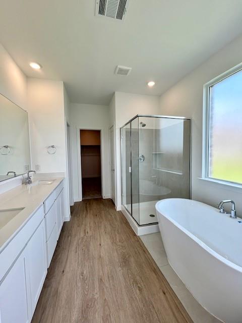 2204 Greenbelt Road Celina, TX 75009 - Photo 4 of 9 Modern bathroom featuring wood-finish flooring, a freestanding bathtub, and a glass-enclosed shower