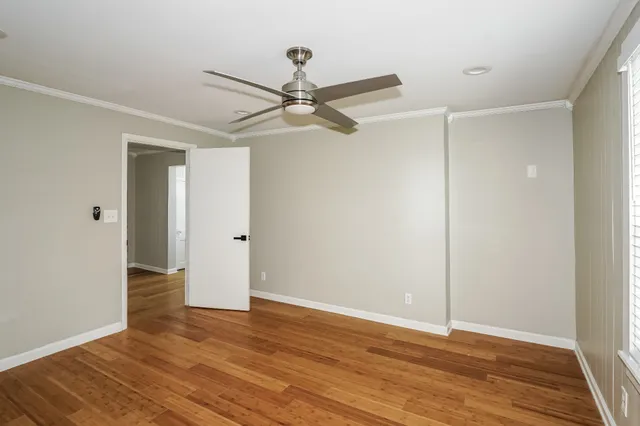an empty room with wooden floor fan and windows