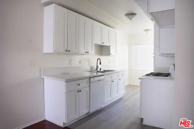 a kitchen with granite countertop a sink stove and cabinets