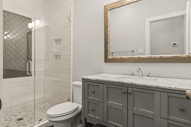 a bathroom with a granite countertop toilet sink shower and mirror